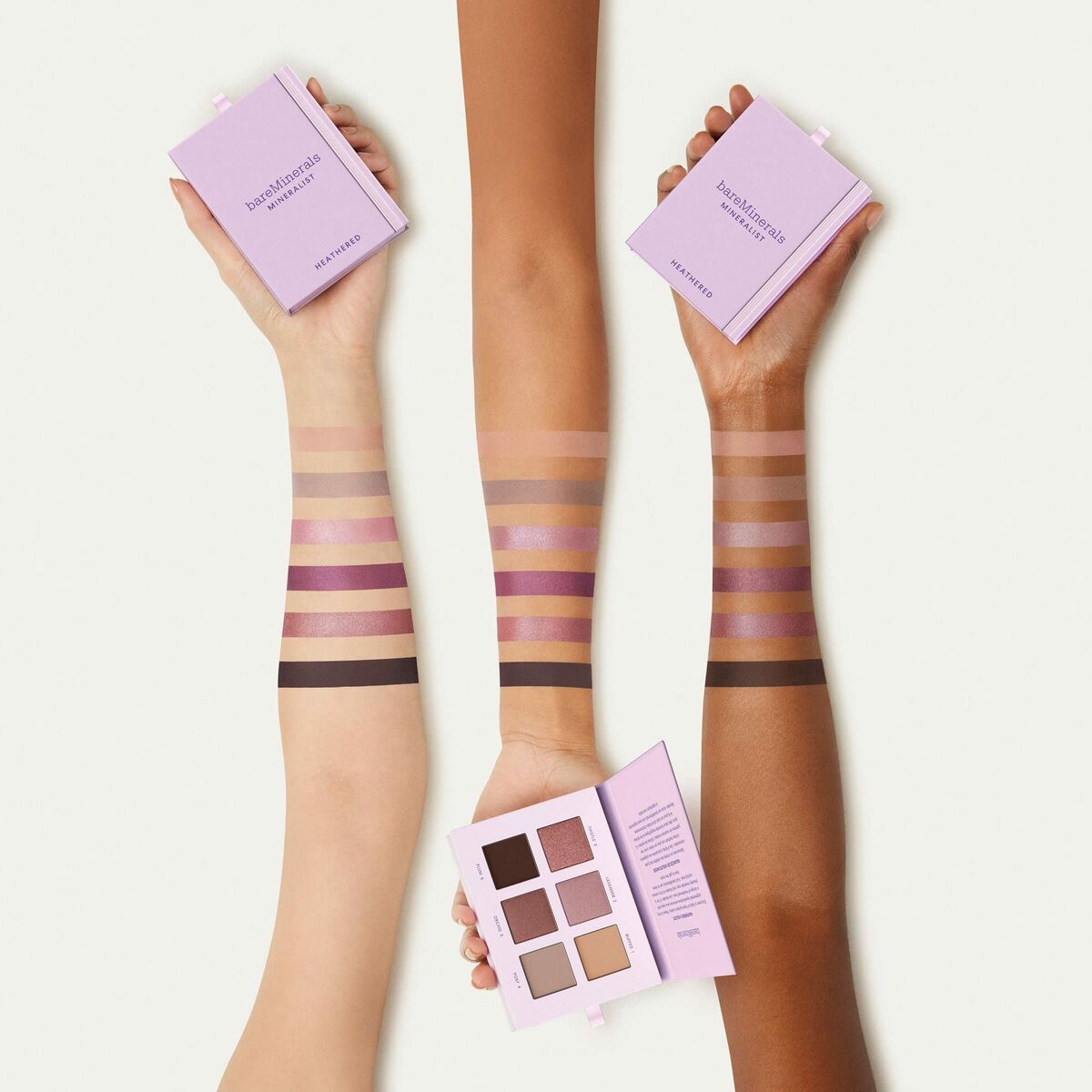 Diverse skin tones displaying swatches of eyeshadow with packaging from the brand, showcasing color variety and inclusivity.
