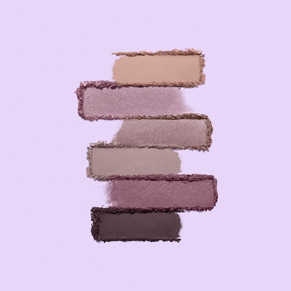 Swatches of mineral makeup shades in soft, neutral tones on a light lavender background.