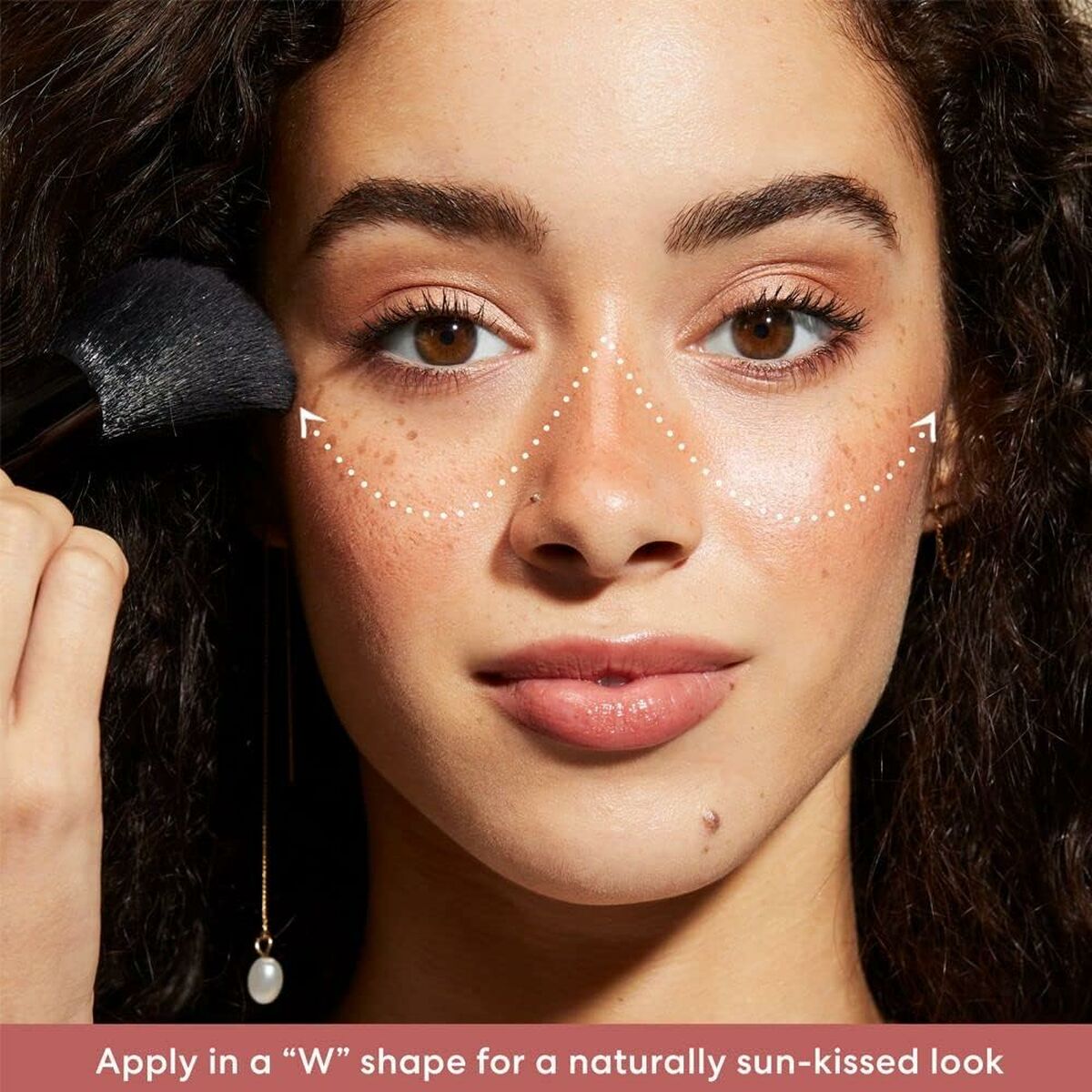 Young woman applying makeup in a 'W' shape for a sun-kissed look with a brush.