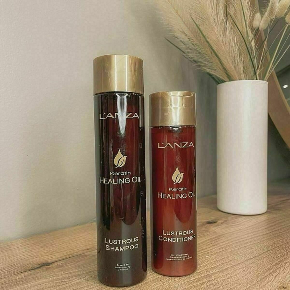 L'ANZA Keratin Healing Oil shampoo and conditioner bottles on wooden table, perfect for all hair types.