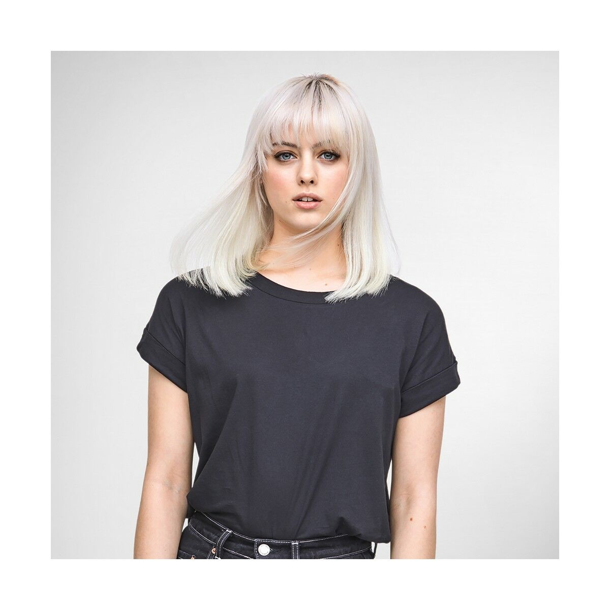 Stylish woman with straight blonde hair wearing a black t-shirt, posing confidently.