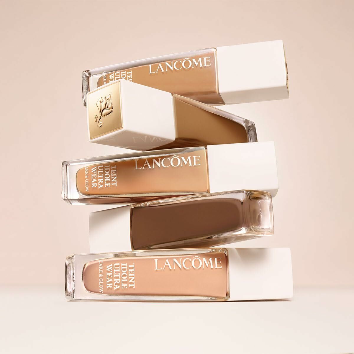 Lancôme Teint Idole Ultra Wear foundation bottles stacked on a light background, showcasing a range of shades.