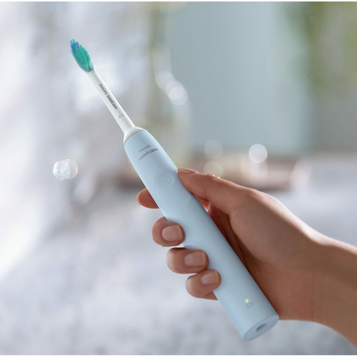 Brosse à dents électrique Philips en main, coloris bleu, avec tête de brosse souple pour une hygiène buccale améliorée.
